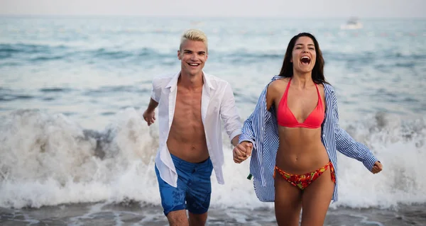 Feliz casal alegre se divertindo em uma praia tropical ao pôr do sol — Fotografia de Stock