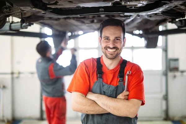 Young auto mechanic working in garage. Repair service.