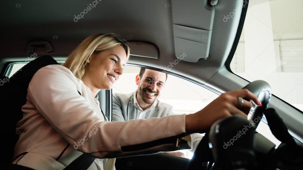 She has bought her dream car. Attractive young woman sitting at the front seat of the car