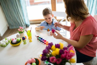 Mutlu genç anne ve oğlu bir tablo tablo Easter egg oturuyor