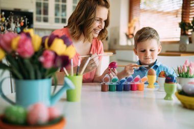 Mutlu genç anne ve oğlu bir tablo tablo Easter egg oturuyor