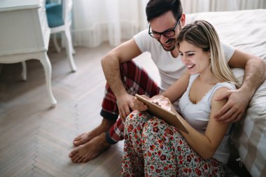 Genç mutlu çift yatak odasında dijital tablet kullanma