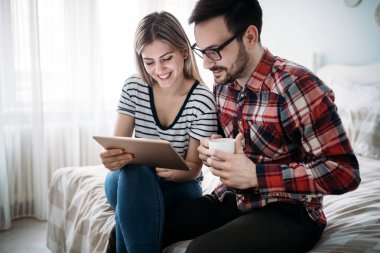 Genç mutlu çift yatak odasında dijital tablet kullanma