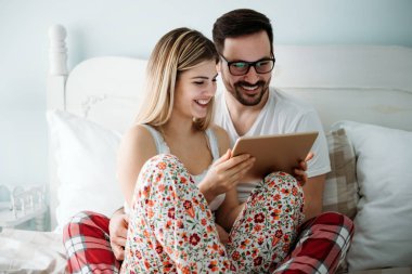 Genç mutlu çift yatak odasında dijital tablet kullanma