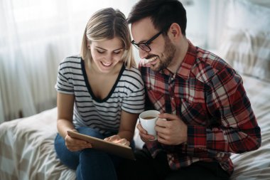 Genç mutlu çift yatak odasında dijital tablet kullanma