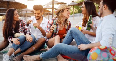 Gülüyor ve sahilde bira içme genç arkadaş grubu