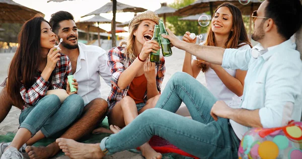Group of young friends laughing and drinking beer at beach