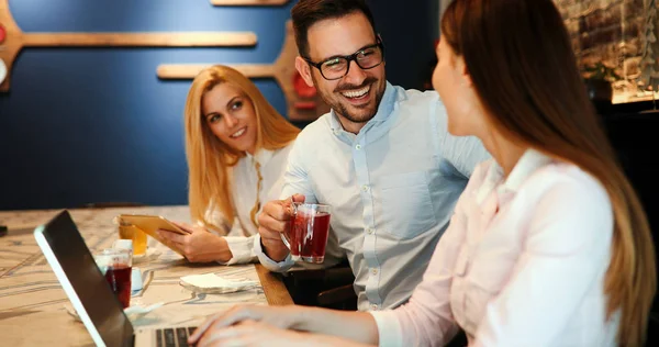 Happy young colleagues from work socializing in restaurant