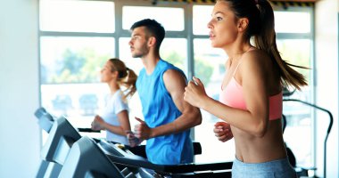 Spor salonunda koşu bandında kardiyo antrenmanı yapan insanların fotoğrafı.