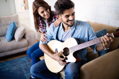 Genç yakışıklı adam güzel kız arkadaşı için gitar çalıyor.