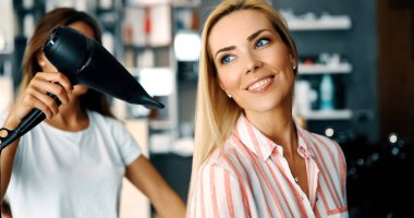 Mutlu genç kadın ve Kuaför Saç salonu stil sıcak yapmak fan ile