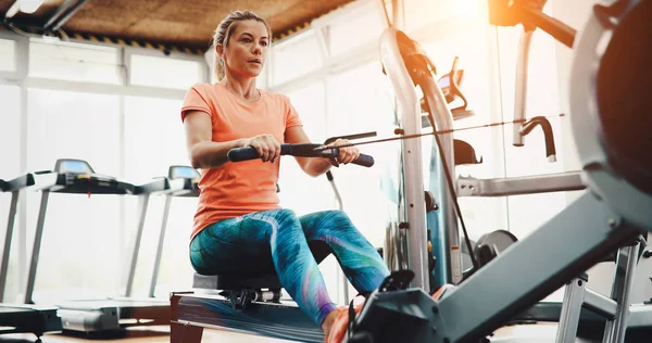 Woman working out in gym on fitness machine
