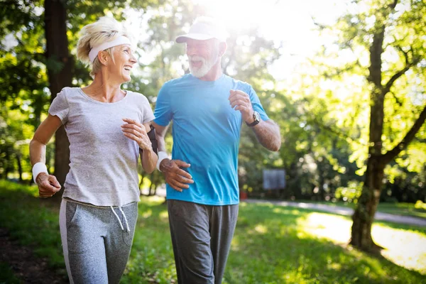 Senior couple jogging and running outdoors in park nature