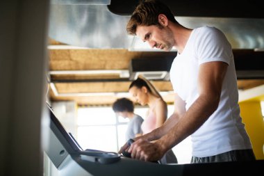 Spor salonunda koşu bandında koşan bir grup sağlıklı genç.