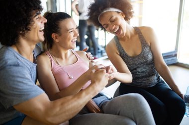 Spor salonunda egzersiz yapan bir grup mutlu genç.