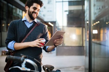 Tablet ve kahveyi dışarıda tutan genç bir adamın portresi