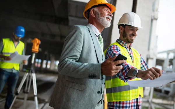 Mühendis, ustabaşı ve işçi inşaat alanında tartışıyor ve çalışıyor.