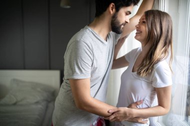 Güzel genç aşıklar evde sevgi ve şefkatle kucaklaşıyorlar.