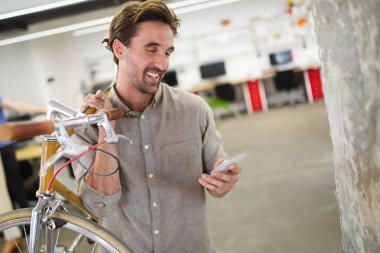 Modern ofiste Bisiklet taşıyan mutlu işadamı