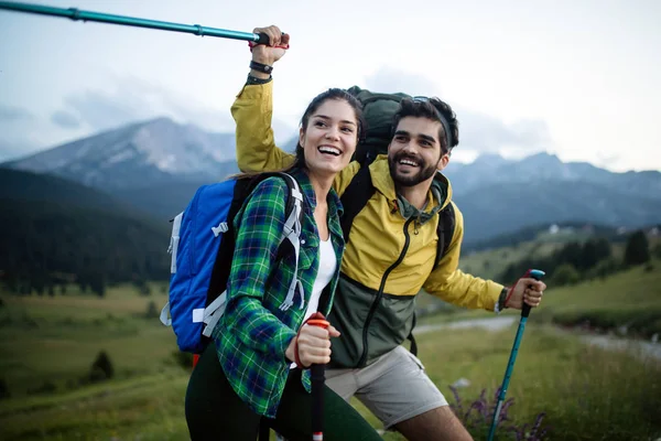 Backpackers happy beautiful couple hiking with sticks