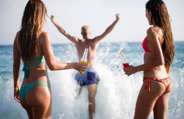 Bir grup mutlu arkadaş yazın sahilde içki içip eğleniyorlar.