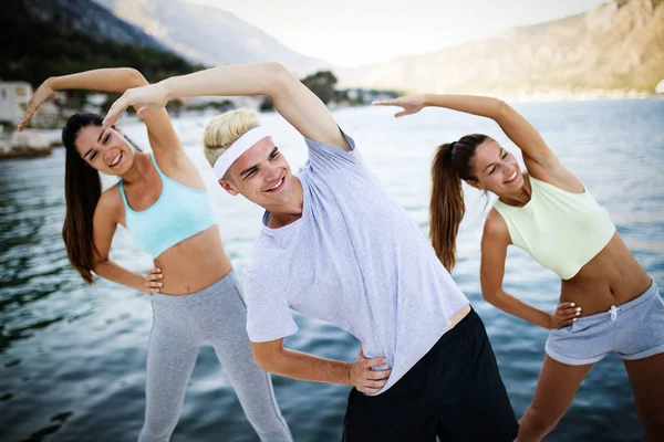 Fitness, sport, friendship and healthy lifestyle concept. Group of happy friends or sportsmen exercising and stretching outdoor