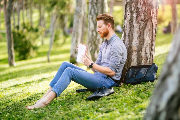 ハンサムな学生の読書と公園で勉強して — ストック写真