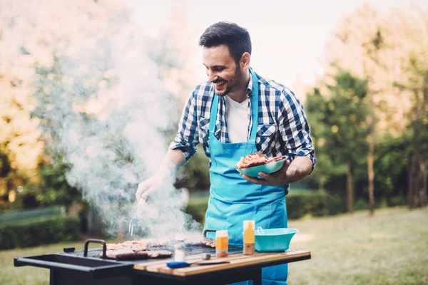 自然の屋外バーベキューの肉を焼く幸せな男性 — ストック写真