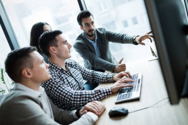 Modern ofis içinde bilgisayar üzerinde çalışan genç iş adamları
