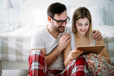 Genç mutlu çift yatak odasında tablet kullanıyor.