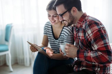 Genç mutlu çift yatak odasında tablet kullanıyor.