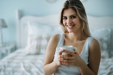 Evde yatakta yalnız oturan genç güzel kadın