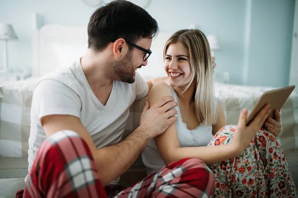 Genç mutlu çift yatak odasında tablet kullanıyor.