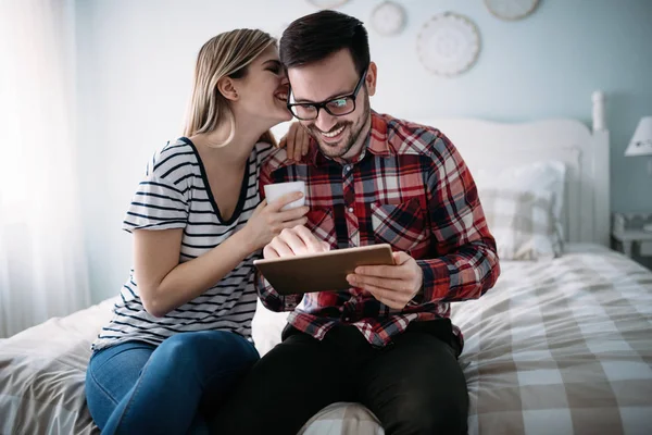 Unga lyckliga par använder tablett i sovrummet — Stockfoto