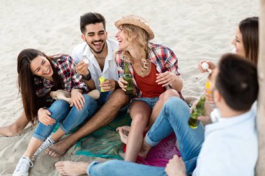 Gülüyor ve sahilde bira içme genç arkadaş grubu