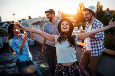 Bir grup mutlu genç arkadaş çatıda parti veriyor.