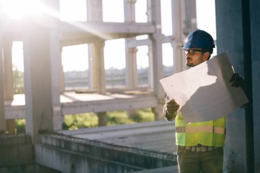 Genç iş adamı inşaat sitesi mühendis mavi baskı ile
