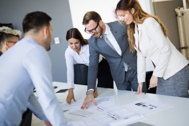 Takım inşaat planları üzerinde birlikte çalışan mimarlar