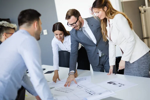 Takım inşaat planları üzerinde birlikte çalışan mimarlar