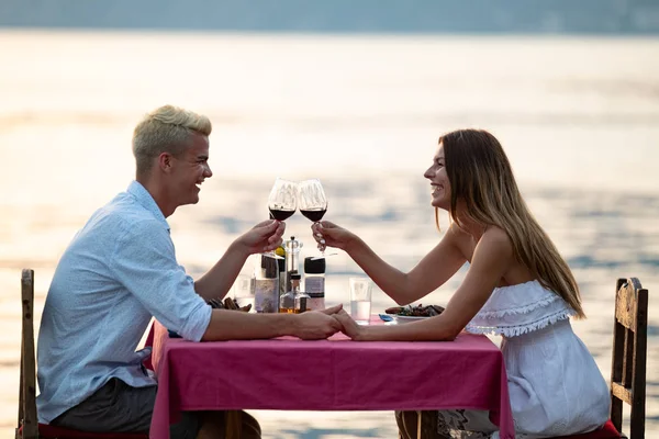 İnsanlar, kutlama, tatil, balayı ve romantizm konsepti. Genç çift sahilde romantik bir akşam yemeği yiyor..