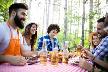 Açık havada barbekü akşam yemeği bira içme ve yemek yeme mutlu arkadaş grubu