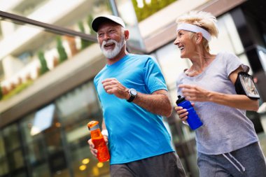 Kadın kıdemli ve koşan adam bir şehirde fitness egzersizleri yapıyor