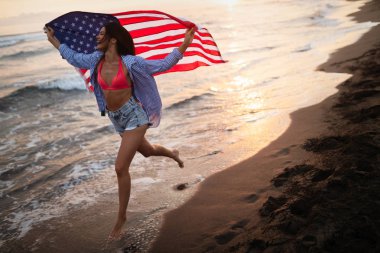 Mutlu kadın gülümseyip plajda koşarken bağımsızlık gününü kutluyor ve Amerika 'da özgürlüğün tadını çıkarıyor.
