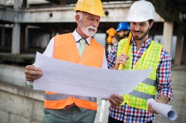 Mimarlar ve mühendislerden oluşan kendinden emin bir ekip modern inşaat alanında birlikte çalışıyor.