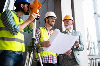 Engineer and construction site manager dealing with blueprints and plans clipart