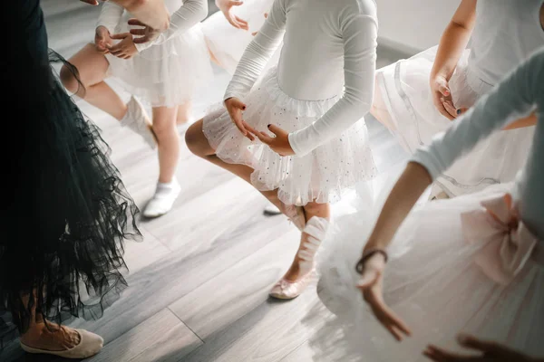 Ballet teacher and group of children ballerinas exercising in ballet school