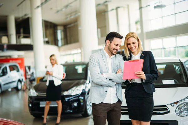 Group of happy beautiful car sales consultants working inside vehicle showroom