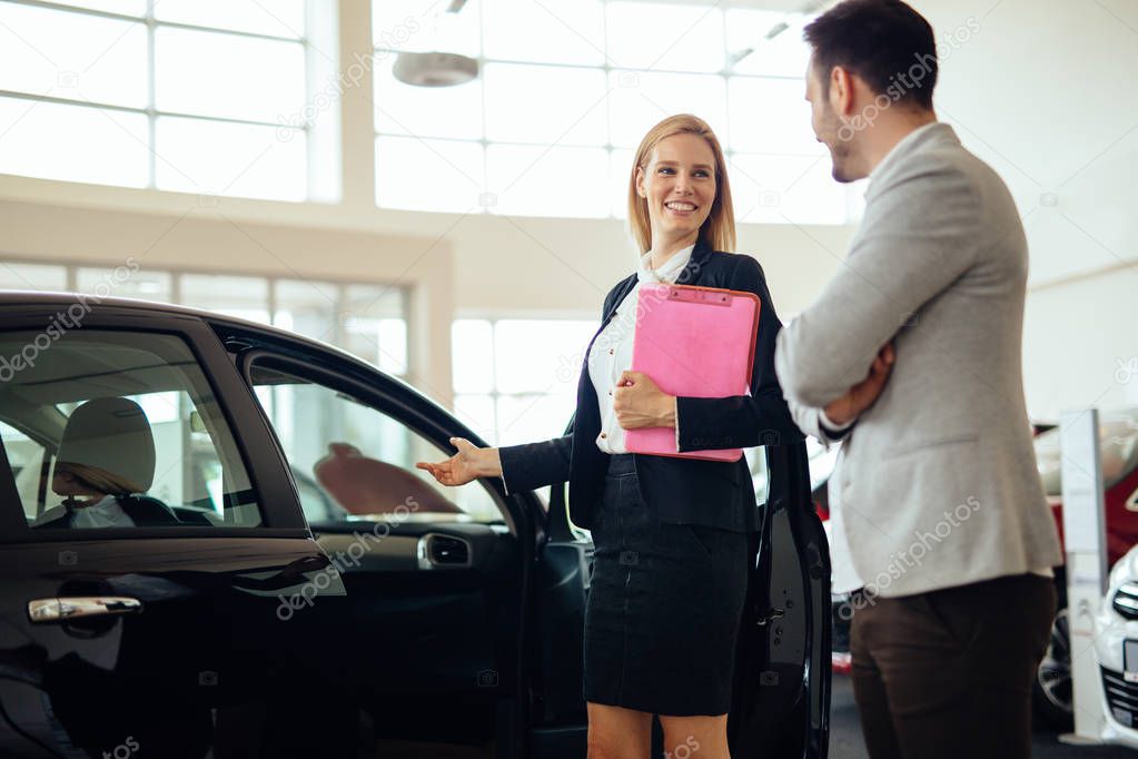 Professional salesperson selling cars at dealership to new buyer