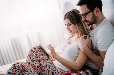 Genç mutlu çift yatak odasında dijital tablet kullanma