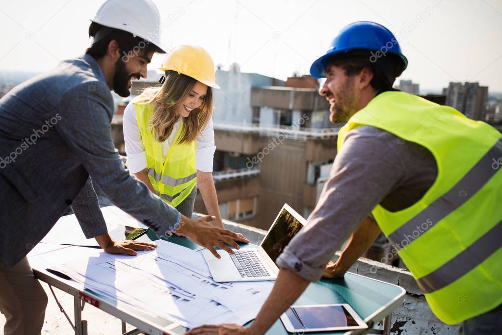 Team of architects and engineers people in group on construciton site check documents